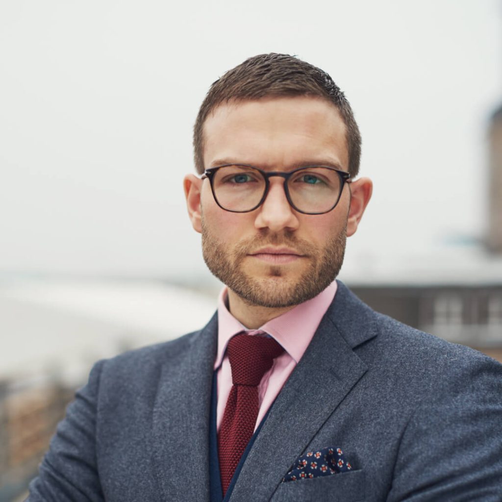 man with glasses and dark hair smiling at the camera