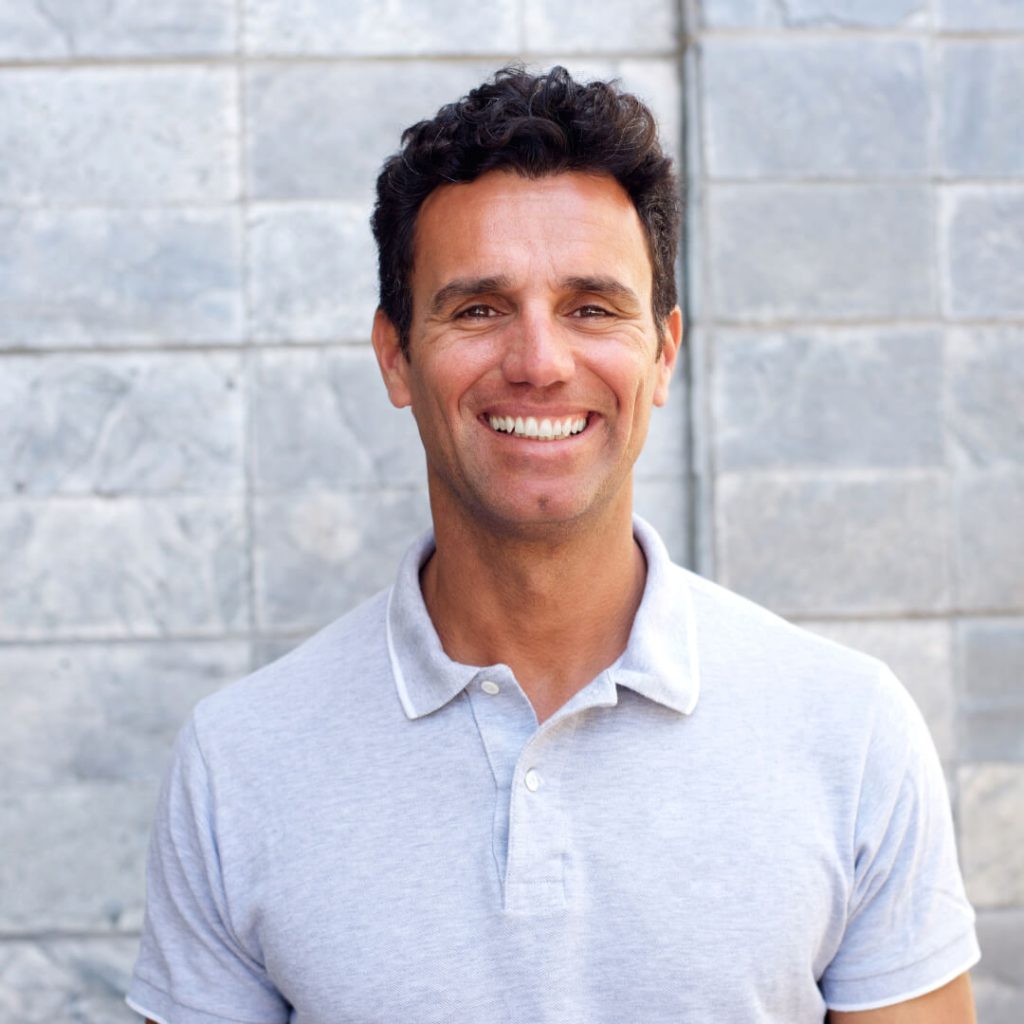 man with dark hair smiling at the camera