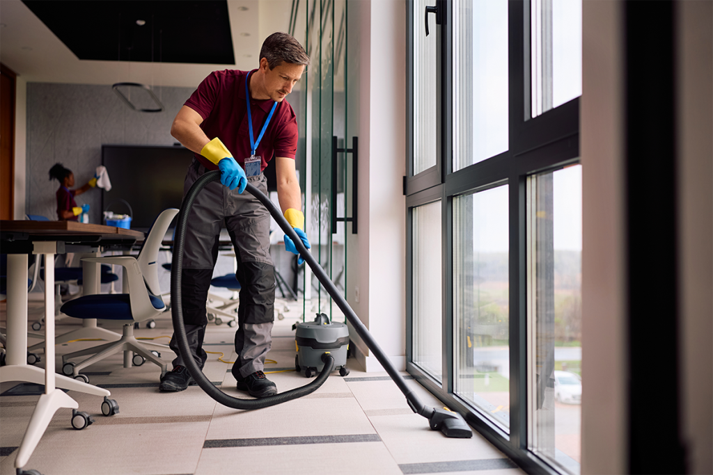 man vacuuming the floor in an office building